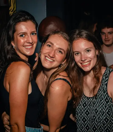 Three friends smiling together on a night out