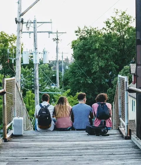 Four friends sitting together on an outdoor boardwalk
