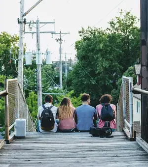 Four friends sitting together on an outdoor boardwalk